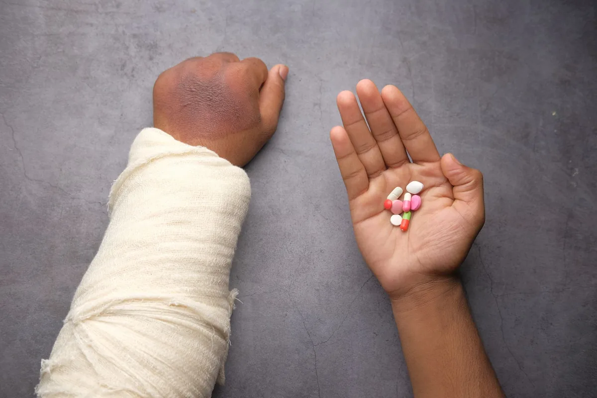 Abogado de lesiones personales en Plano: un brazo vendado junto a un puñado de medicamentos recetados
