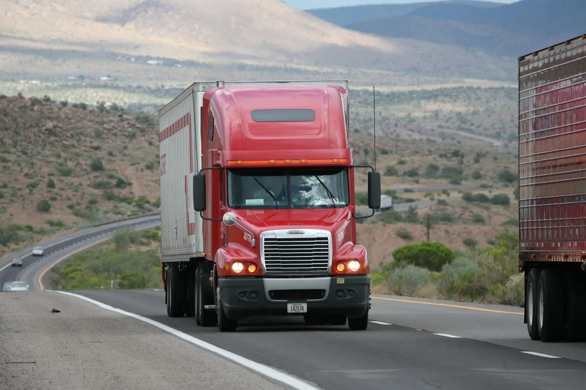 Richardson truck accident lawyer: a red semi truck travelling a highway with its lights on